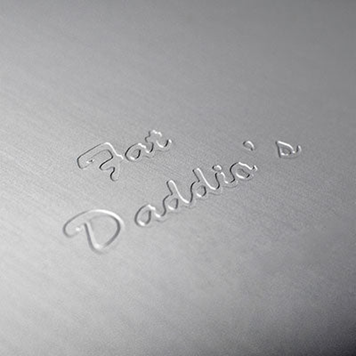 Close-up of Fat Daddio's embossed brand name on the anodized aluminum pan surface