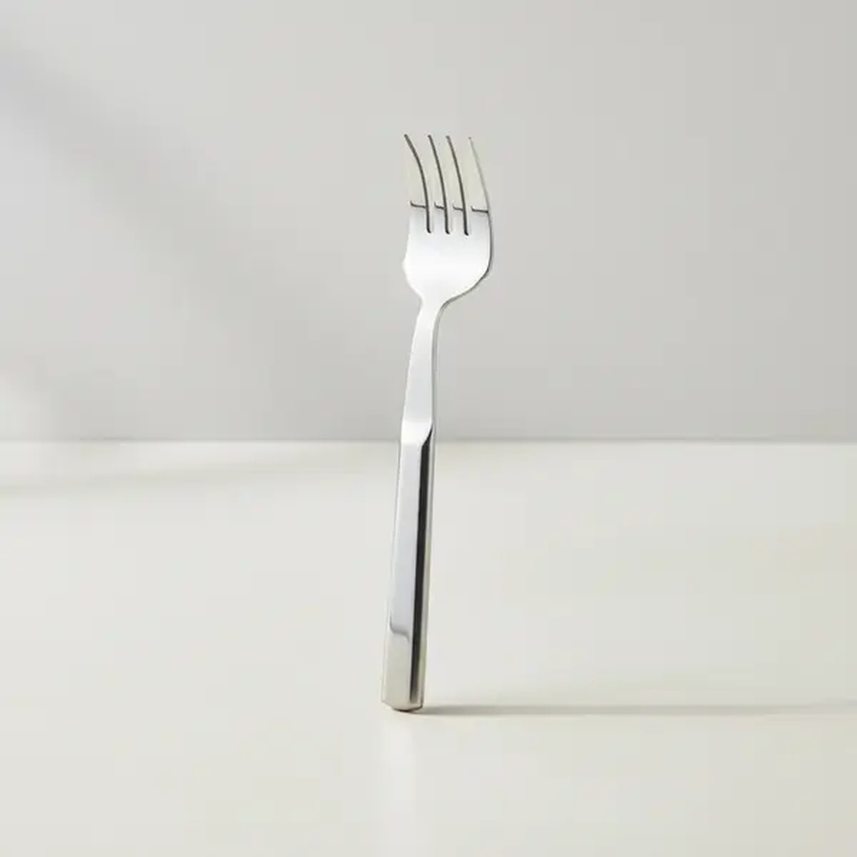 Libertyware BUF4 stainless steel cold meat serving fork standing upright on a white surface