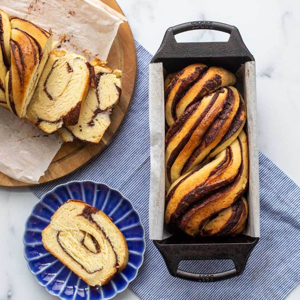 A swirl bread loaf being sliced next to the Lodge cast iron pan
