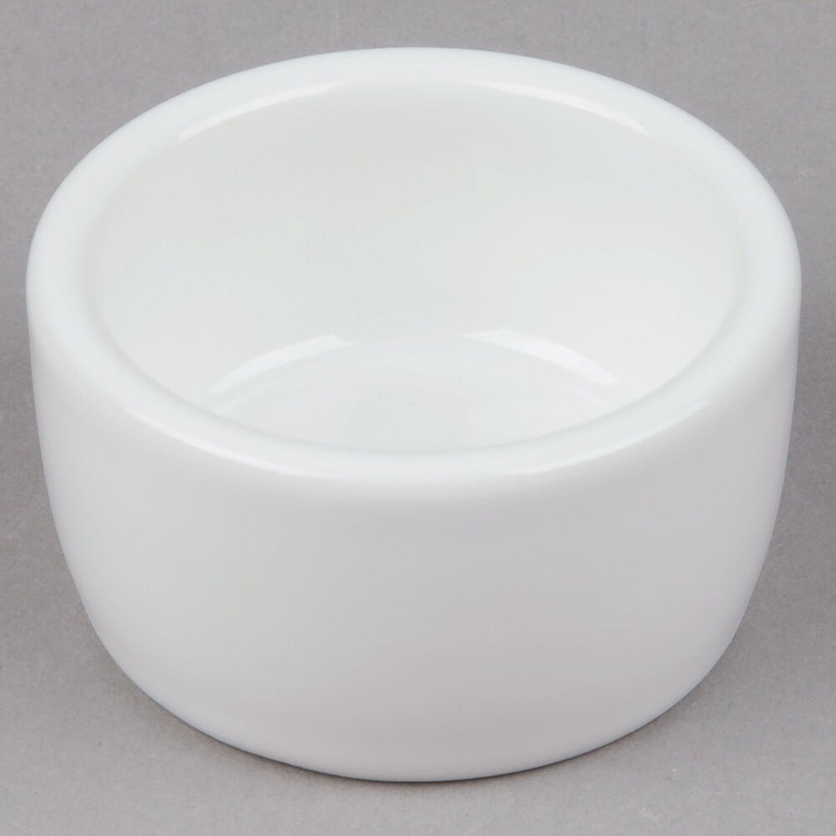 Tuxton BWX-0203 2 oz. white smooth china pipkin ramekin, viewed from a slight angle showing its round shape and open top