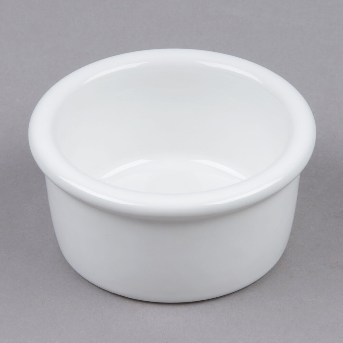 Tuxton BWX-025 white 2.5 oz. smooth china ramekin with rolled edge, viewed from a slight angle