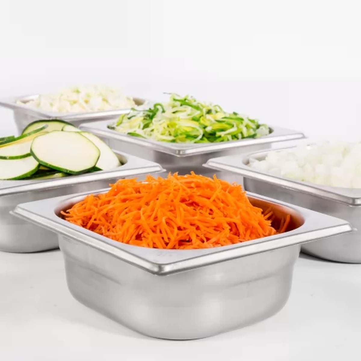 Various sliced and grated vegetables prepared by Sammic CA-41 food processor displayed in hotel pans