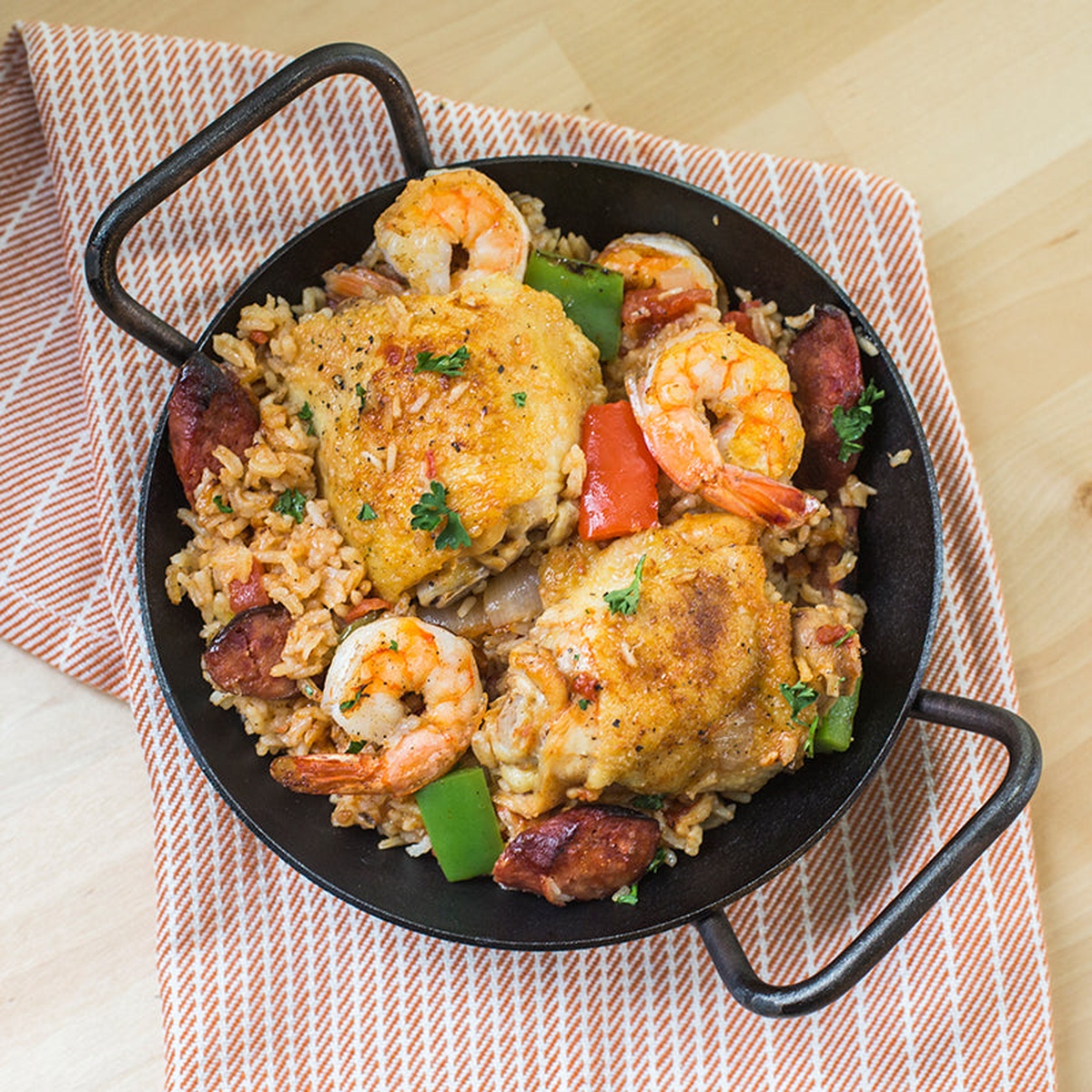 Top down view of a seasoned carbon steel skillet with a colorful paella style meal