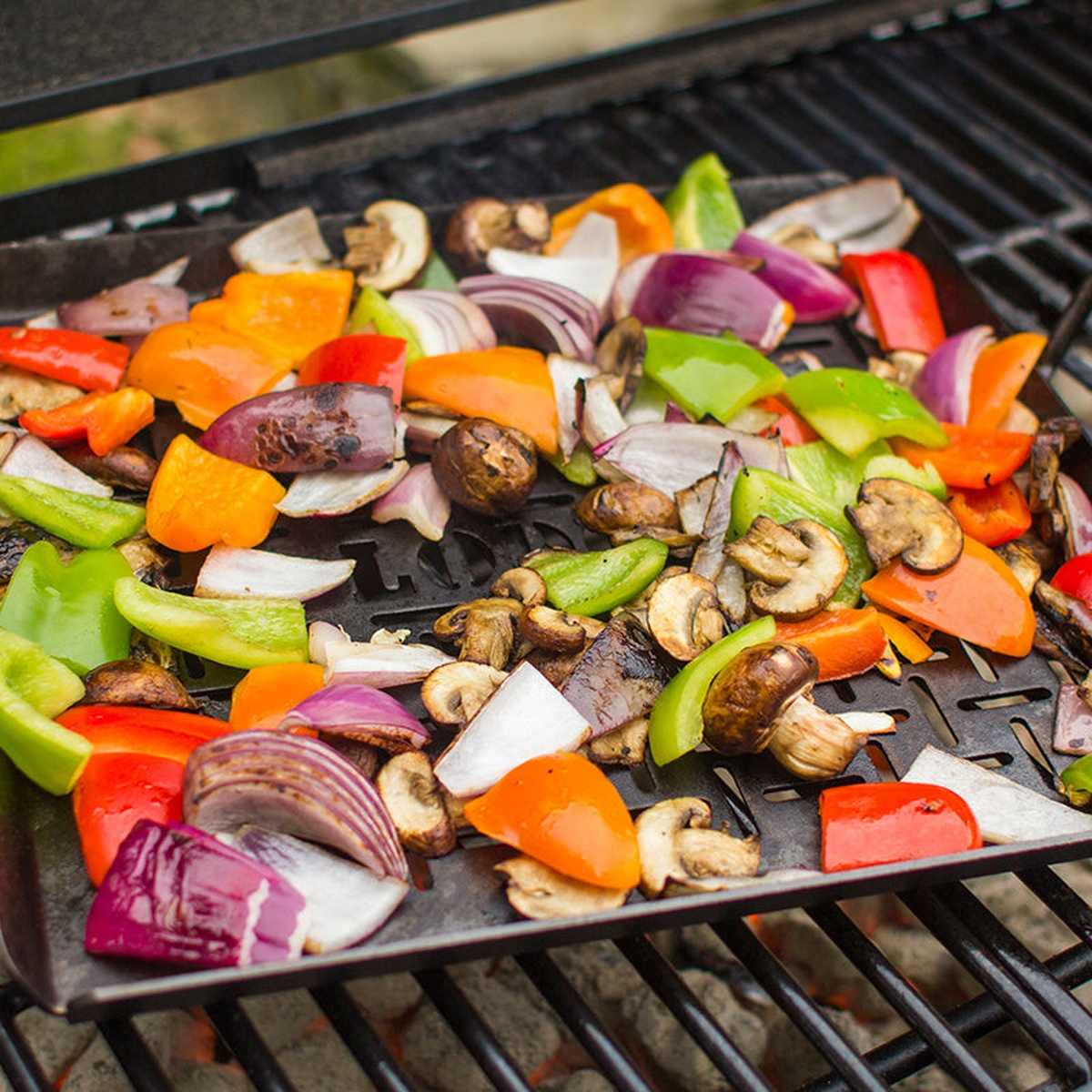 Close up of colorful vegetables cooking in the perforated carbon steel pan