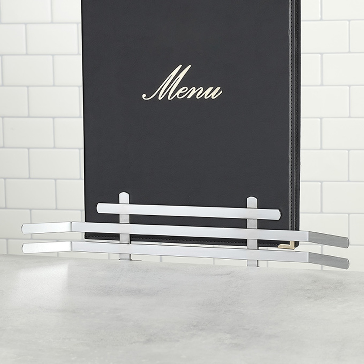 American Metalcraft CS125 menu holder gripping a black leatherette menu cover on a counter surface