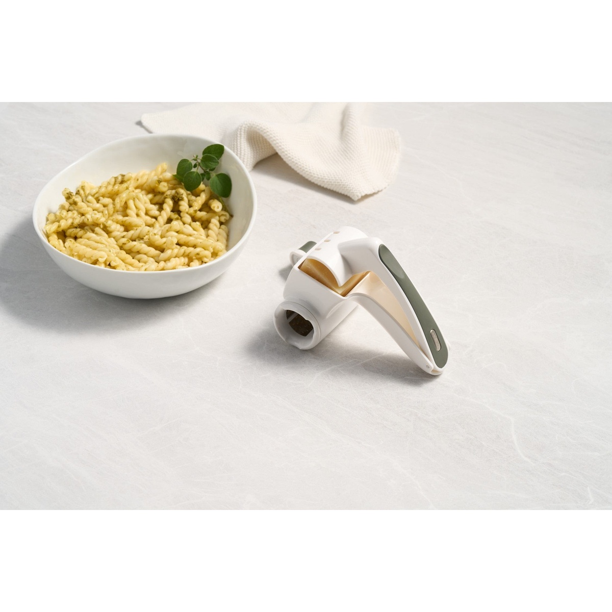 Zyliss Professional Cheese Grater positioned next to a bowl of pasta on a clean light gray surface