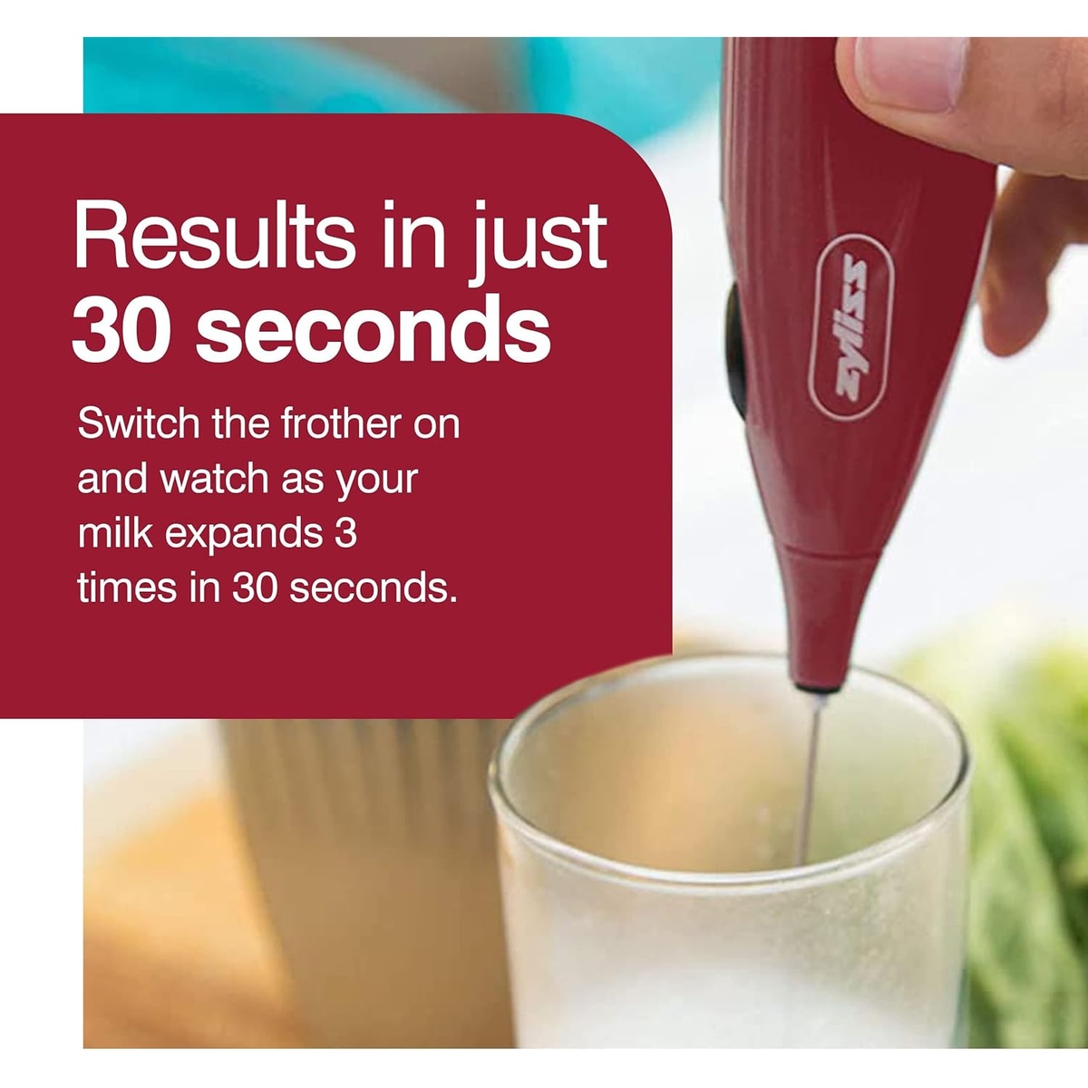 Zyliss red milk frother being inserted into a glass of milk