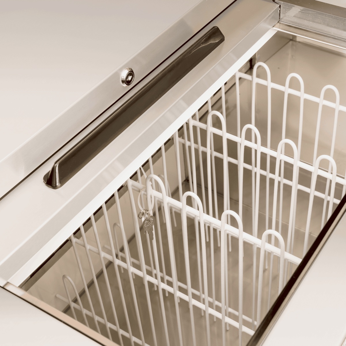 Close-up of EBC-50-HC interior showing white wire bottle dividers and stainless steel liner with slide top door handle and lock