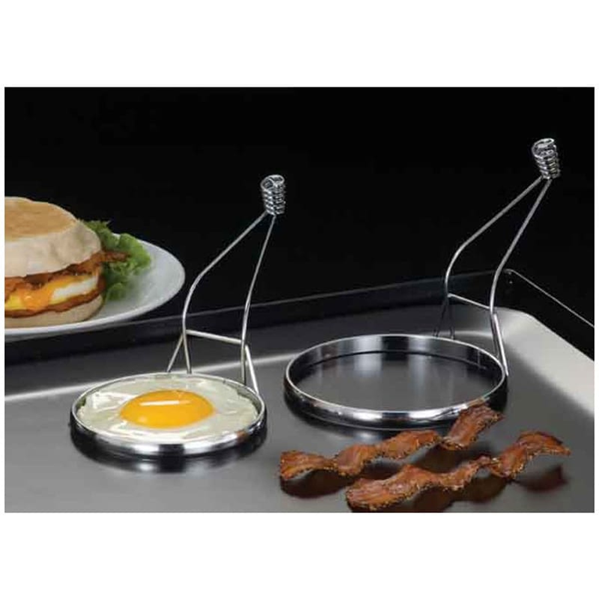 American Metalcraft egg ring being used on a griddle to cook a perfectly round egg next to bacon