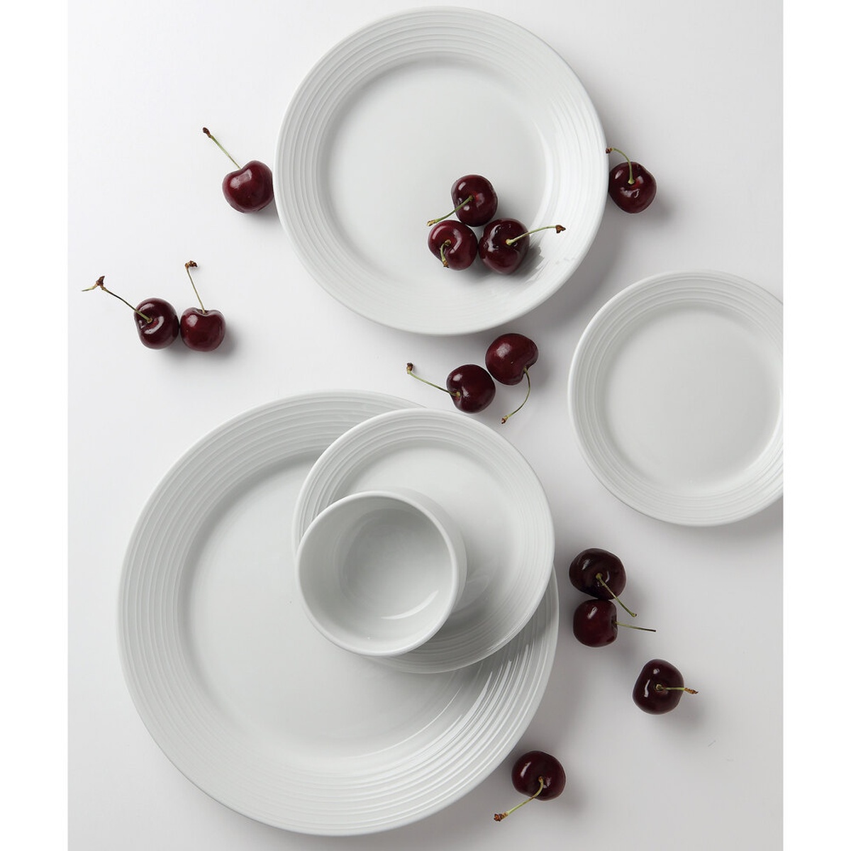 Tuxton Pacifica embossed bright white china dinnerware collection arranged with fresh cherries