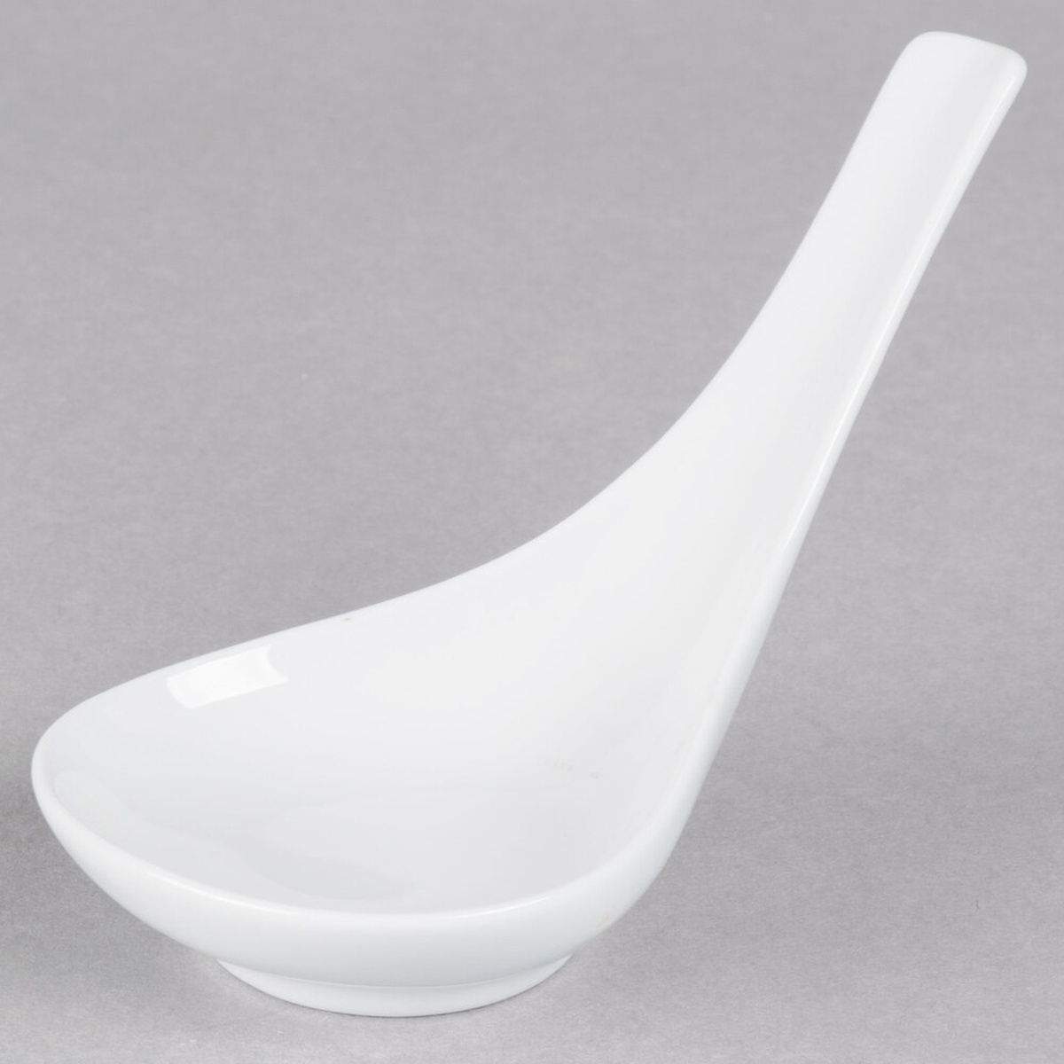 Tuxton GZP-706 porcelain white oval tasting spoon, side profile on gray background