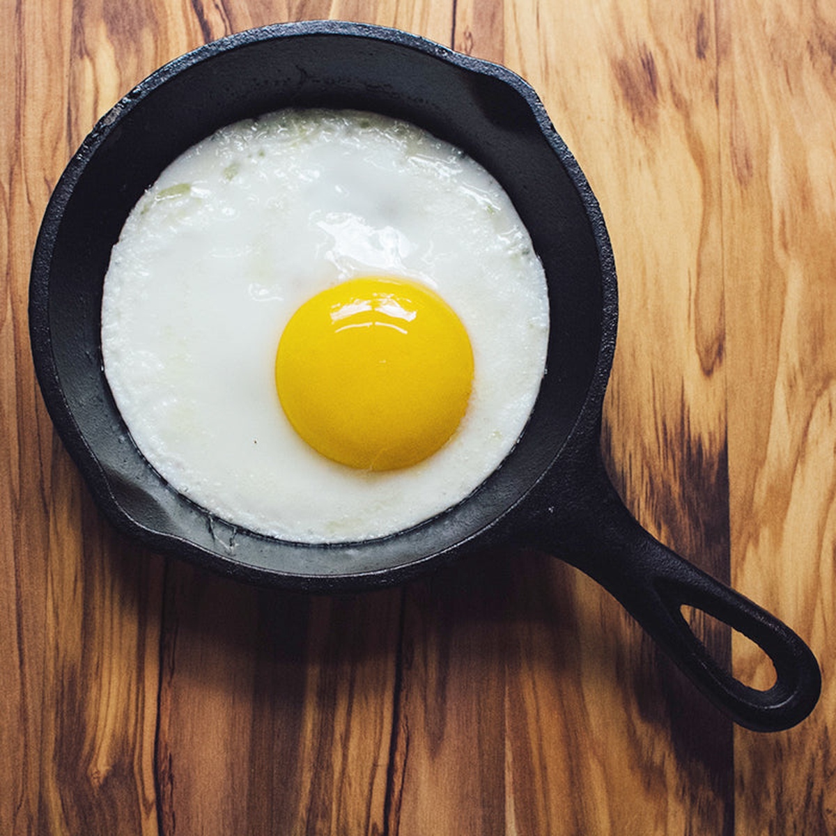 Fried egg cooking in a seasoned cast iron skillet