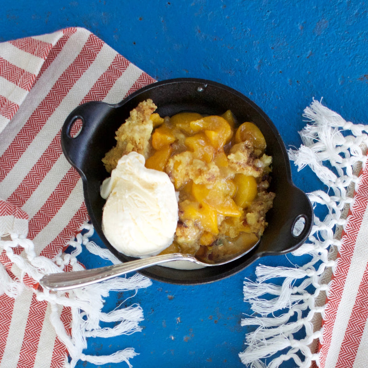 Lodge cast iron mini serving bowl filled with peach cobbler and ice cream