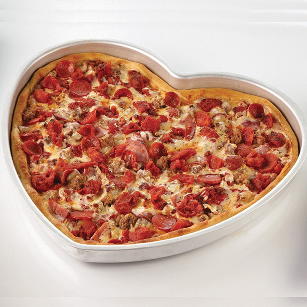 American Metalcraft HPP16 heart-shaped aluminum pizza pan filled with a baked pepperoni pizza