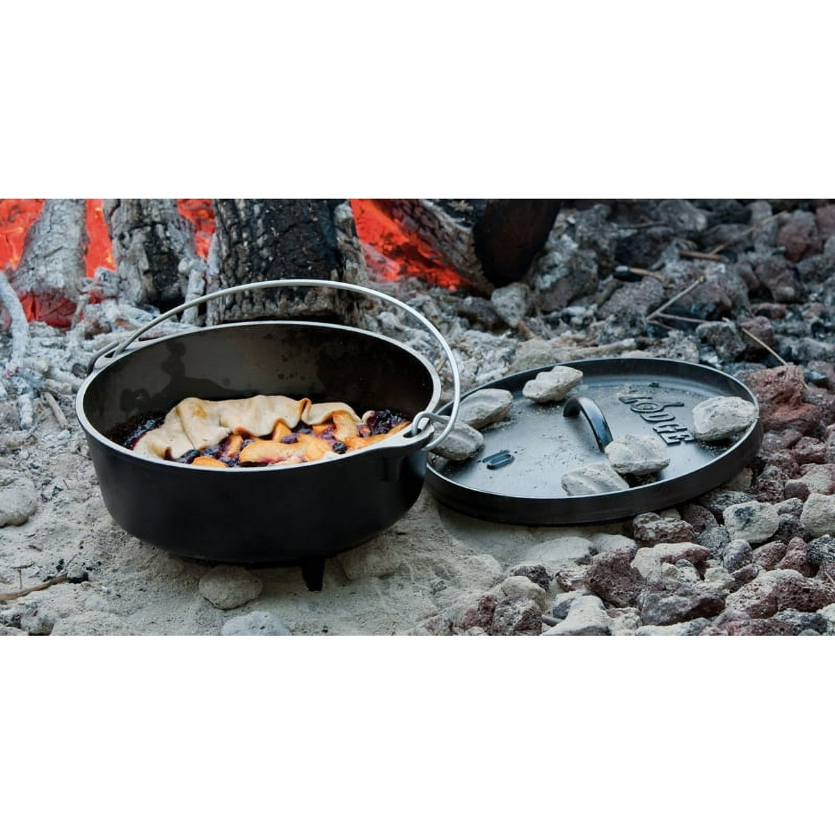 Open Lodge Dutch Oven with food inside and lid with coals on the side