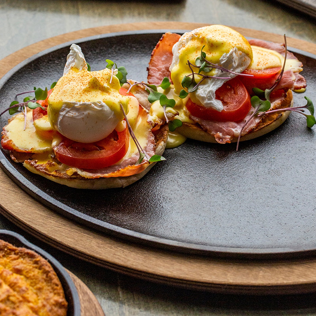 Eggs Benedict served on a sizzling round cast iron platter