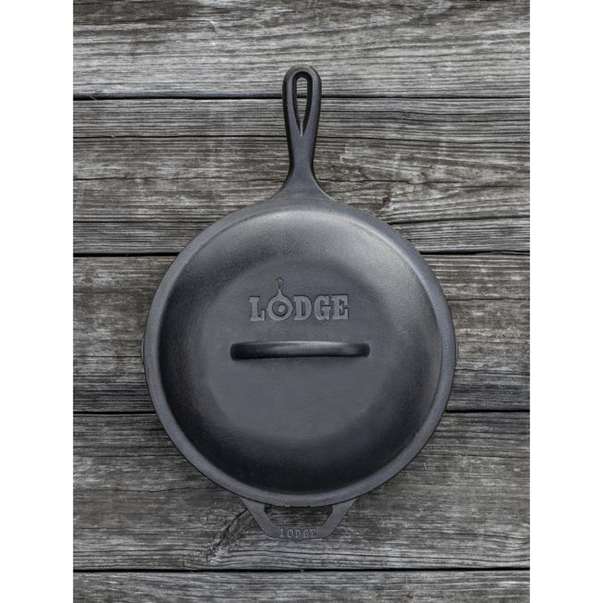 Lodge cast iron lid resting on a Lodge cast iron skillet on a rustic wooden surface, Lodge branding visible