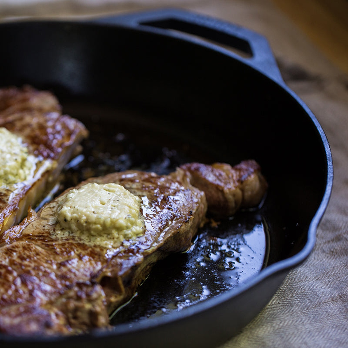 Close up of steaks searing in a Lodge cast iron skillet