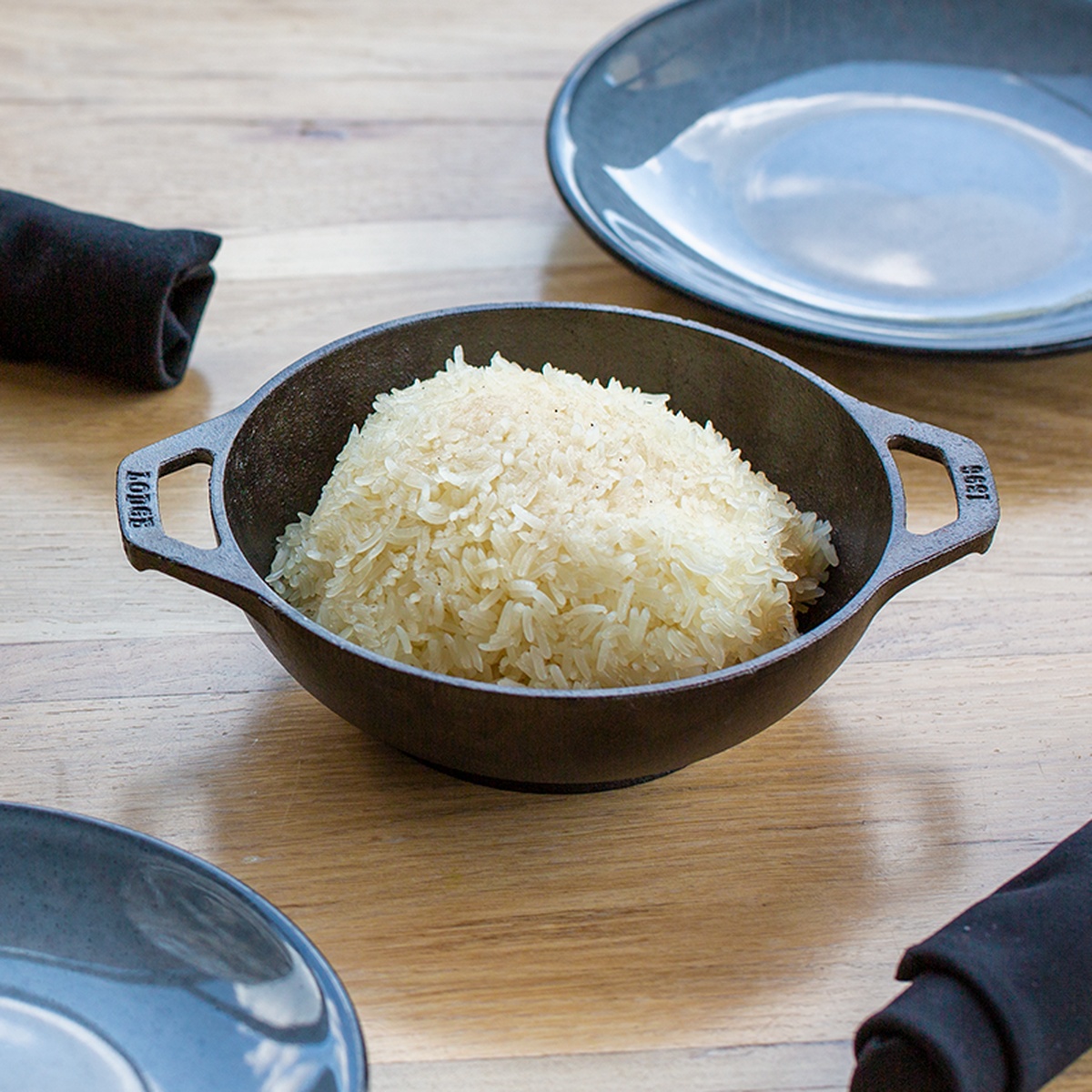 Lodge mini wok used for serving a mound of white rice on a wooden table