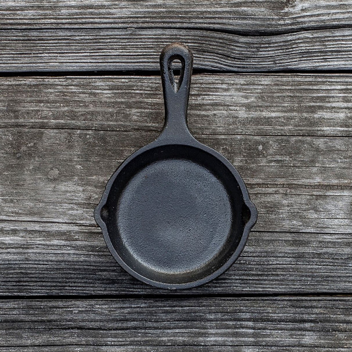 Lodge LMS3 3.5-inch cast iron mini skillet viewed from above on a rustic wooden surface