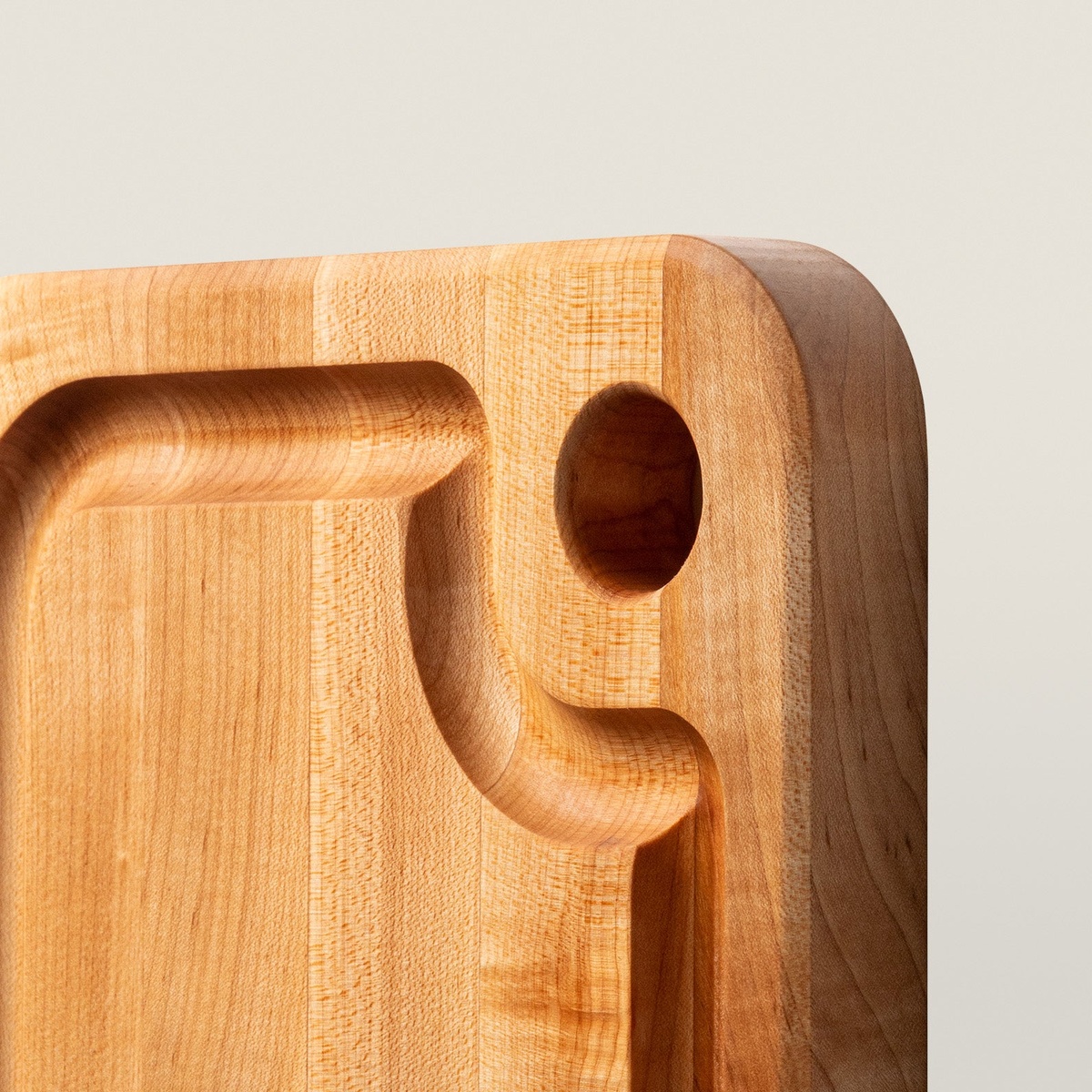 Close-up detail of John Boos maple cutting board showing juice groove channel and finger hole craftsmanship