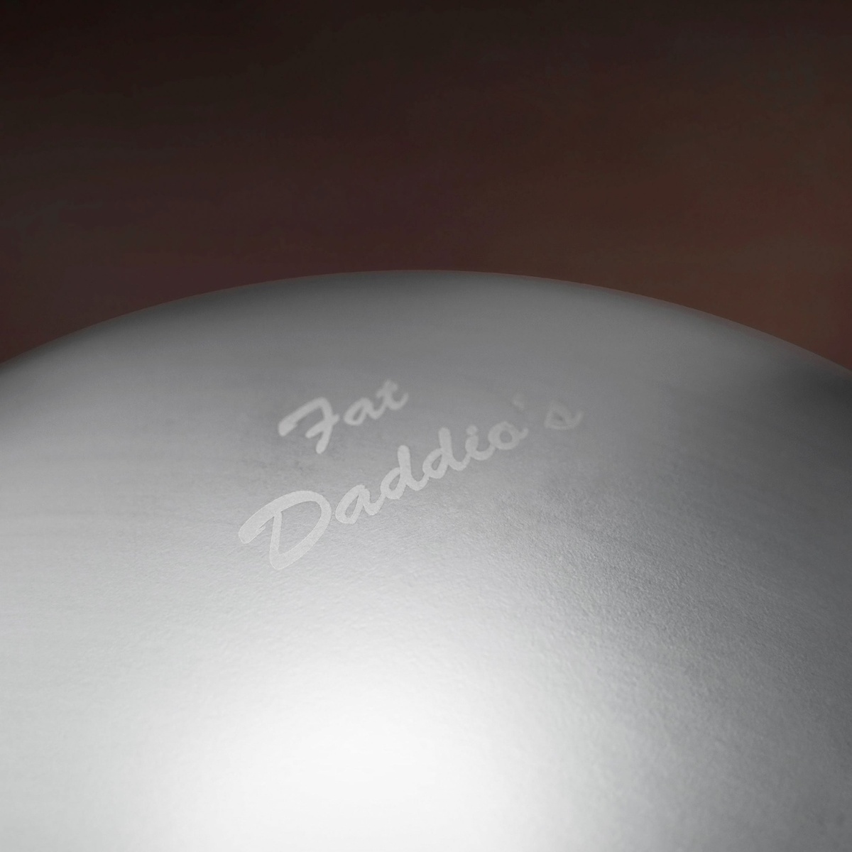 Close-up of the Fat Daddio's logo embossed on the exterior of the anodized aluminum hemisphere pan