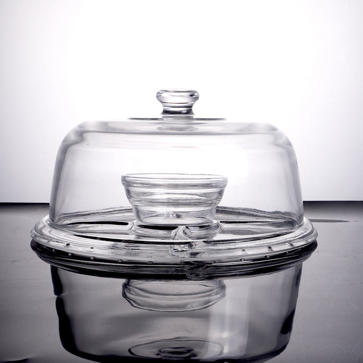Glass cake stand components shown partially assembled with dome cover and base plate