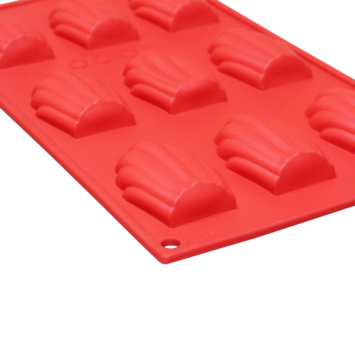 Angled close-up of red silicone madeleine mold showing detailed ridged cavity texture and flexible construction