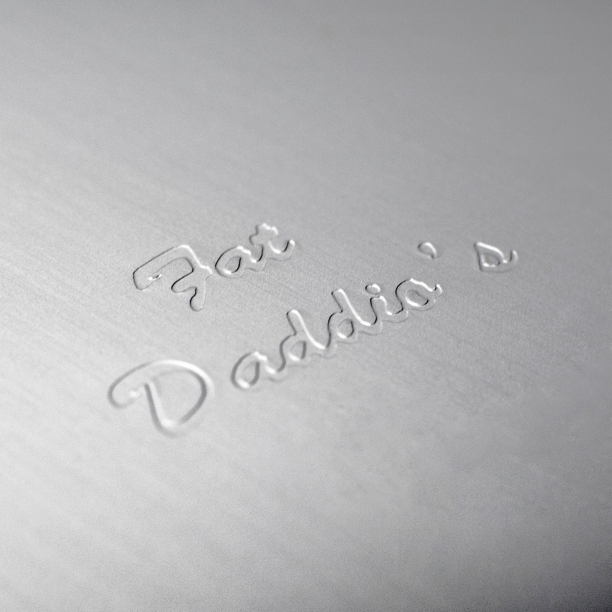 Close-up of embossed Fat Daddio's signature on the anodized aluminum surface of the cake pan