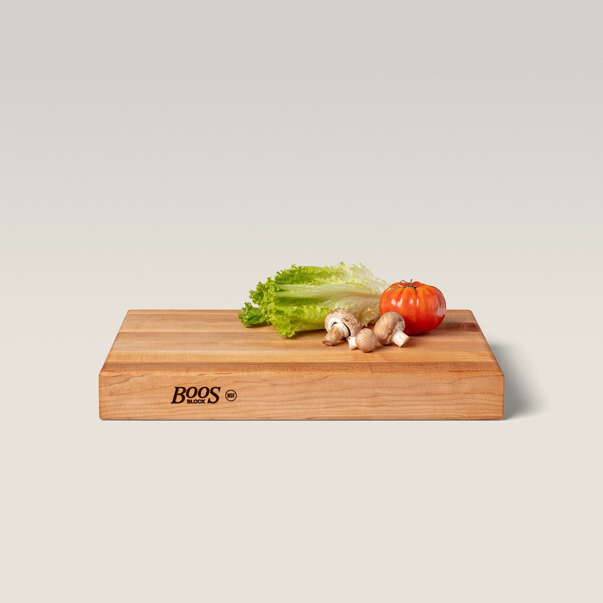 John Boos RA01 cutting board angled view with Boos Block NSF branding on side, fresh vegetables resting on top