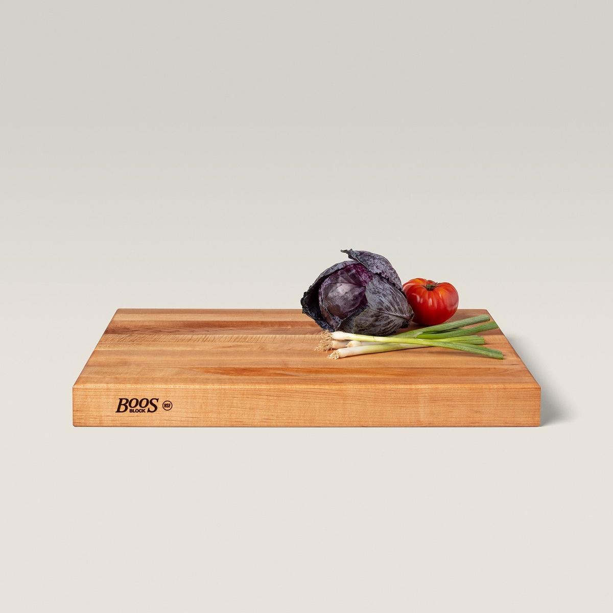 John Boos RA03 maple cutting board shown at an angle with vegetables resting on top, Boos Block NSF branding on the side