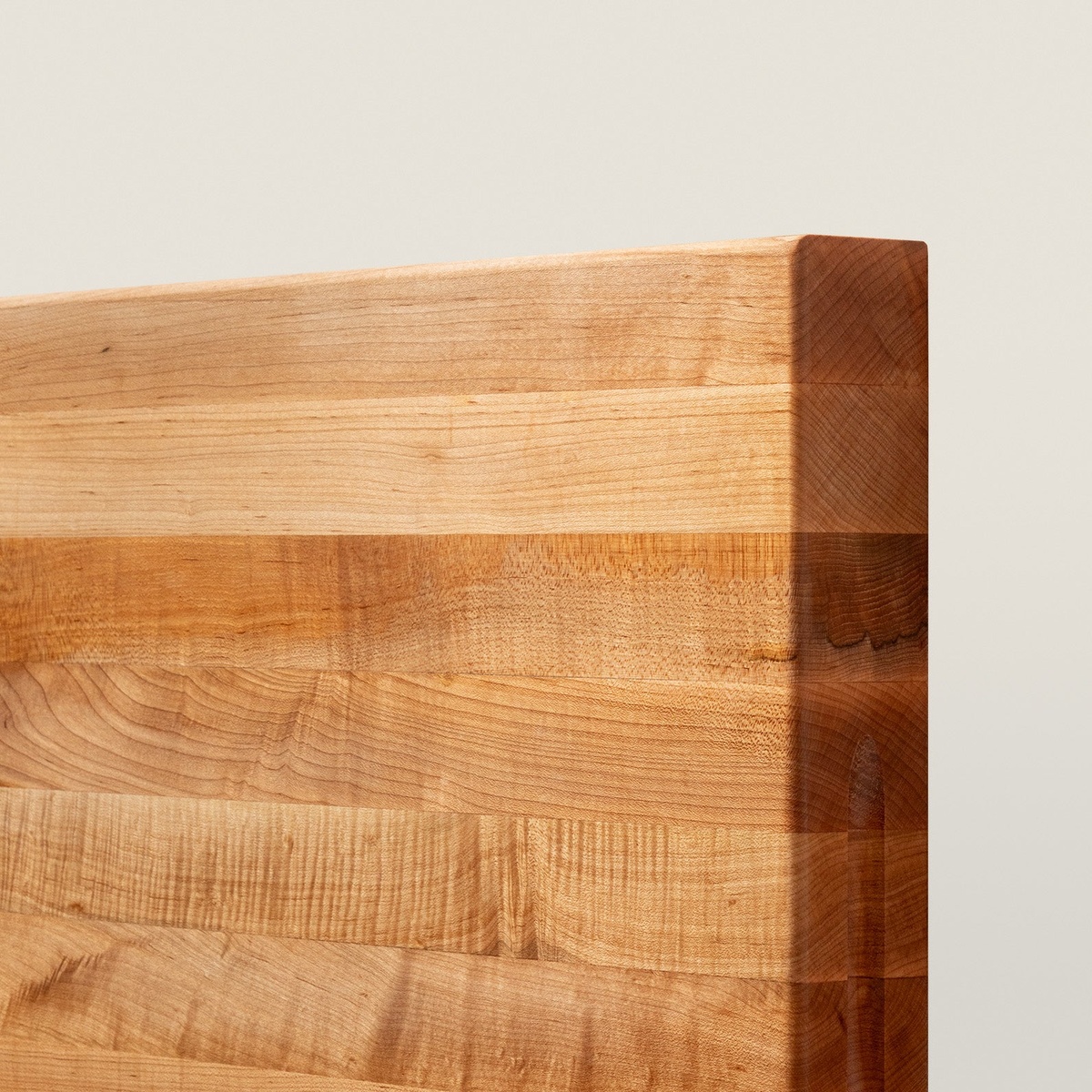Close-up detail of the John Boos RA03 maple cutting board corner, highlighting the edge-grain maple lamination and thick profile