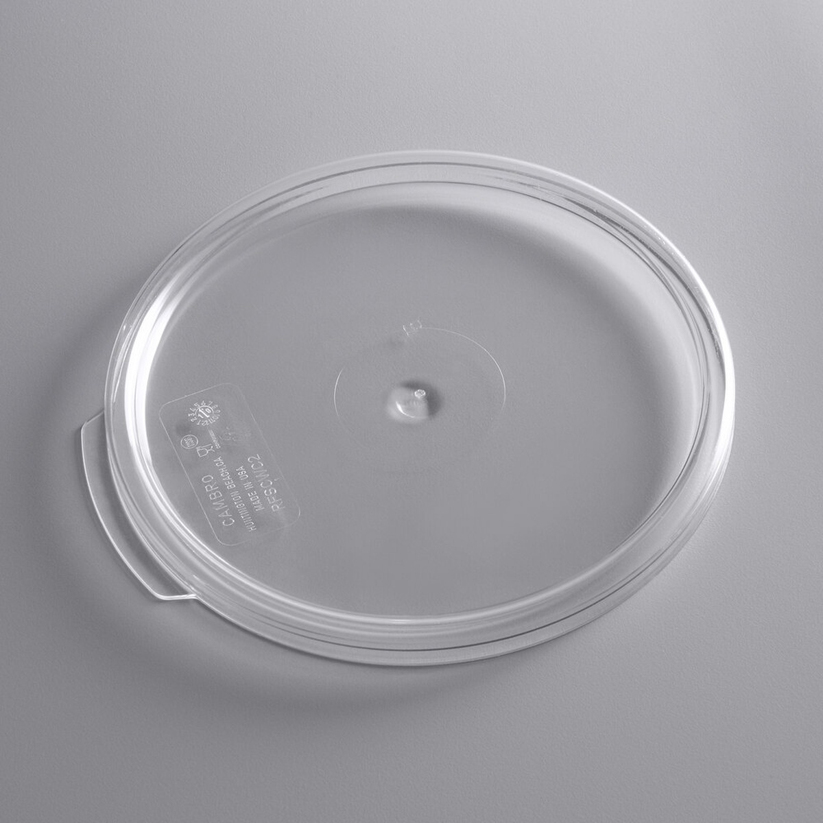 Cambro RFSCWC2135 clear round polycarbonate lid viewed from above at an angle, showing thumb tab and Cambro markings
