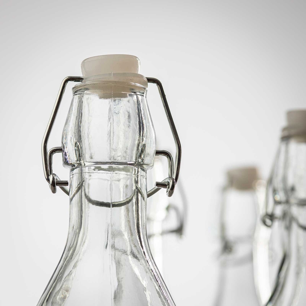 Close-up detail of the wire bail swing top mechanism and white ceramic stopper on the Tablecraft RSB33 glass bottle