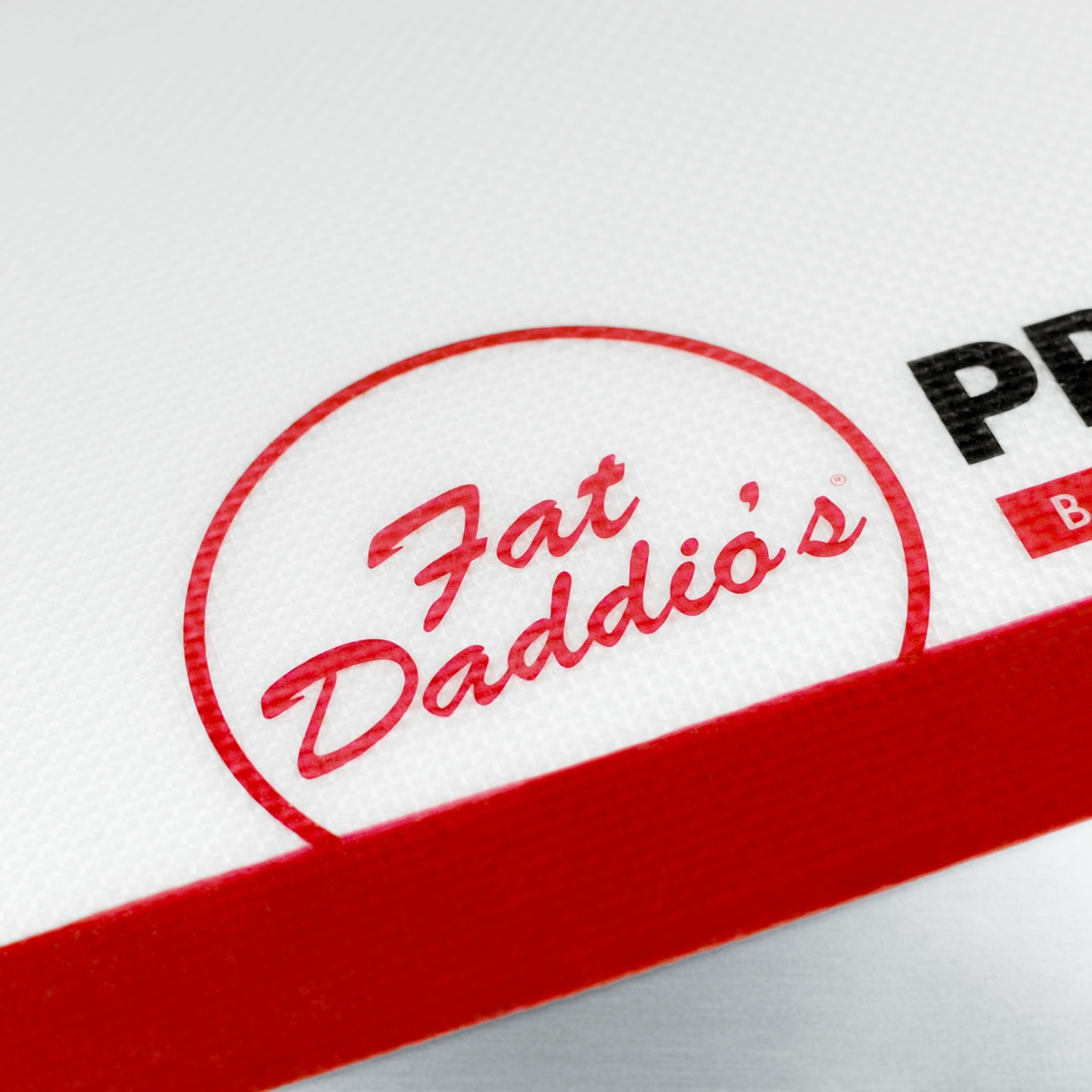Close-up of Fat Daddio's branding and red border ruler on the silicone mat surface
