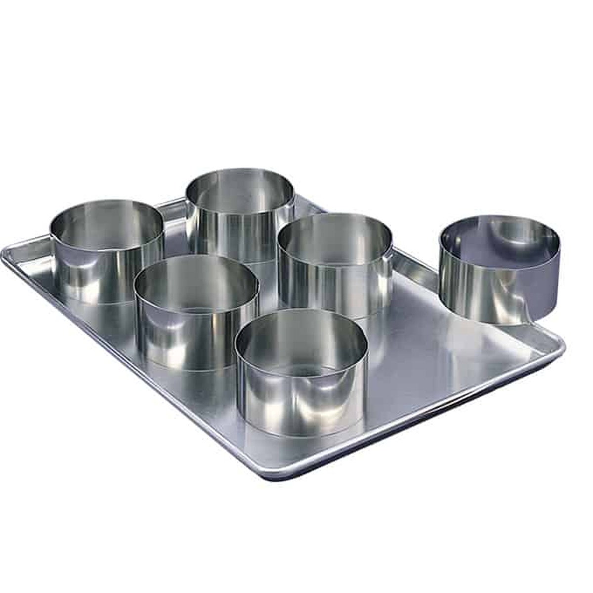 Multiple stainless steel cake rings placed upright on a rectangular aluminum baking sheet