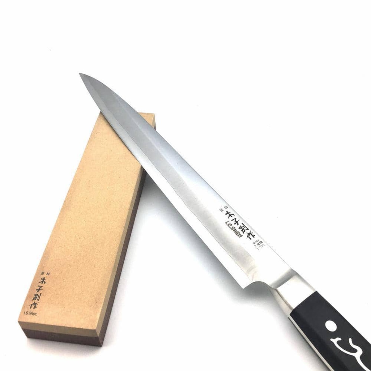 A stainless steel chef knife being sharpened on the Master Grade whetstone