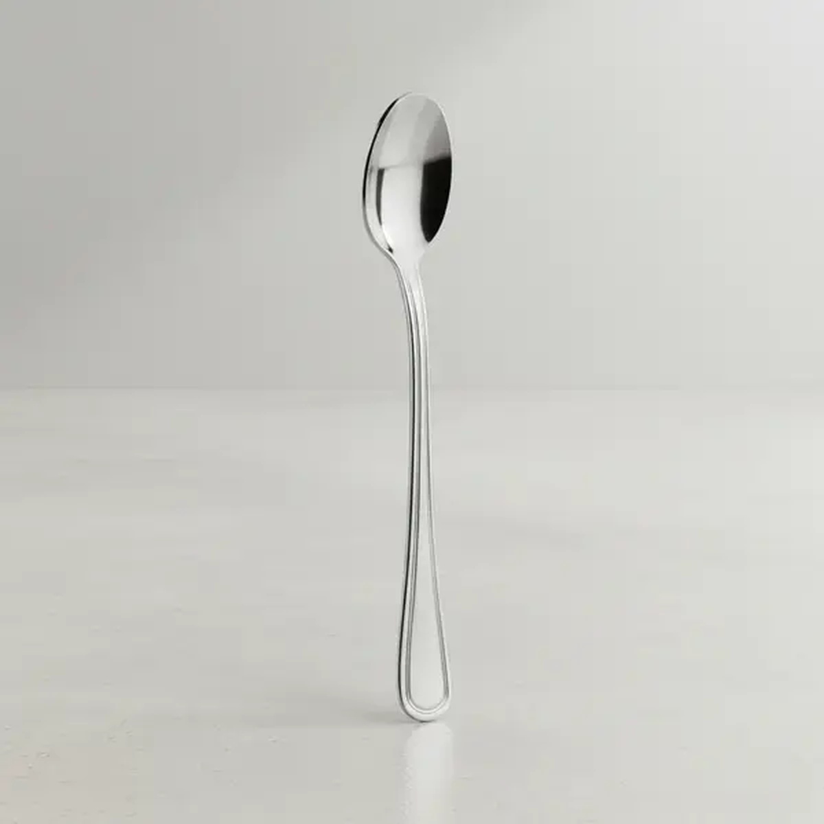 Libertyware STA6 Stansbury iced tea spoon in mirror-polished 18/0 stainless steel, standing upright on a light surface