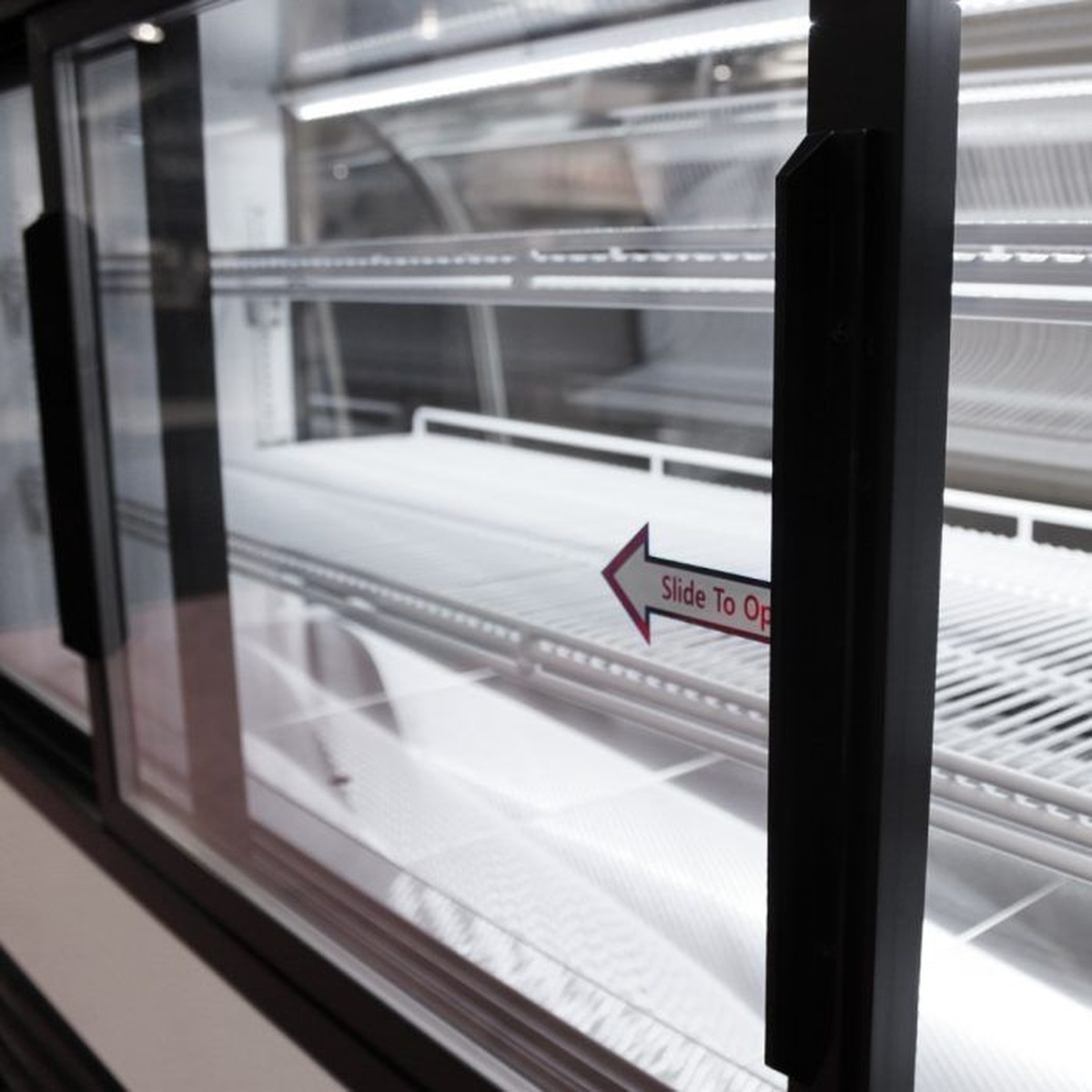 Close-up of the sliding rear glass door on the Turbo Air bakery display case showing interior LED-lit wire shelving