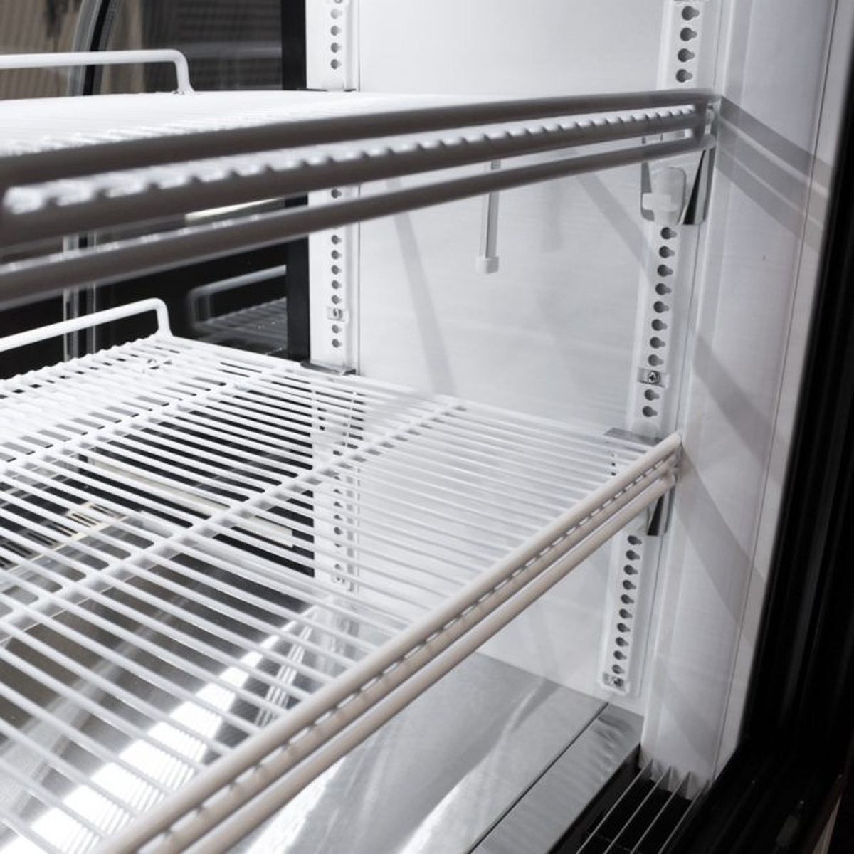 Close-up of adjustable white PE coated wire shelf inside the display case