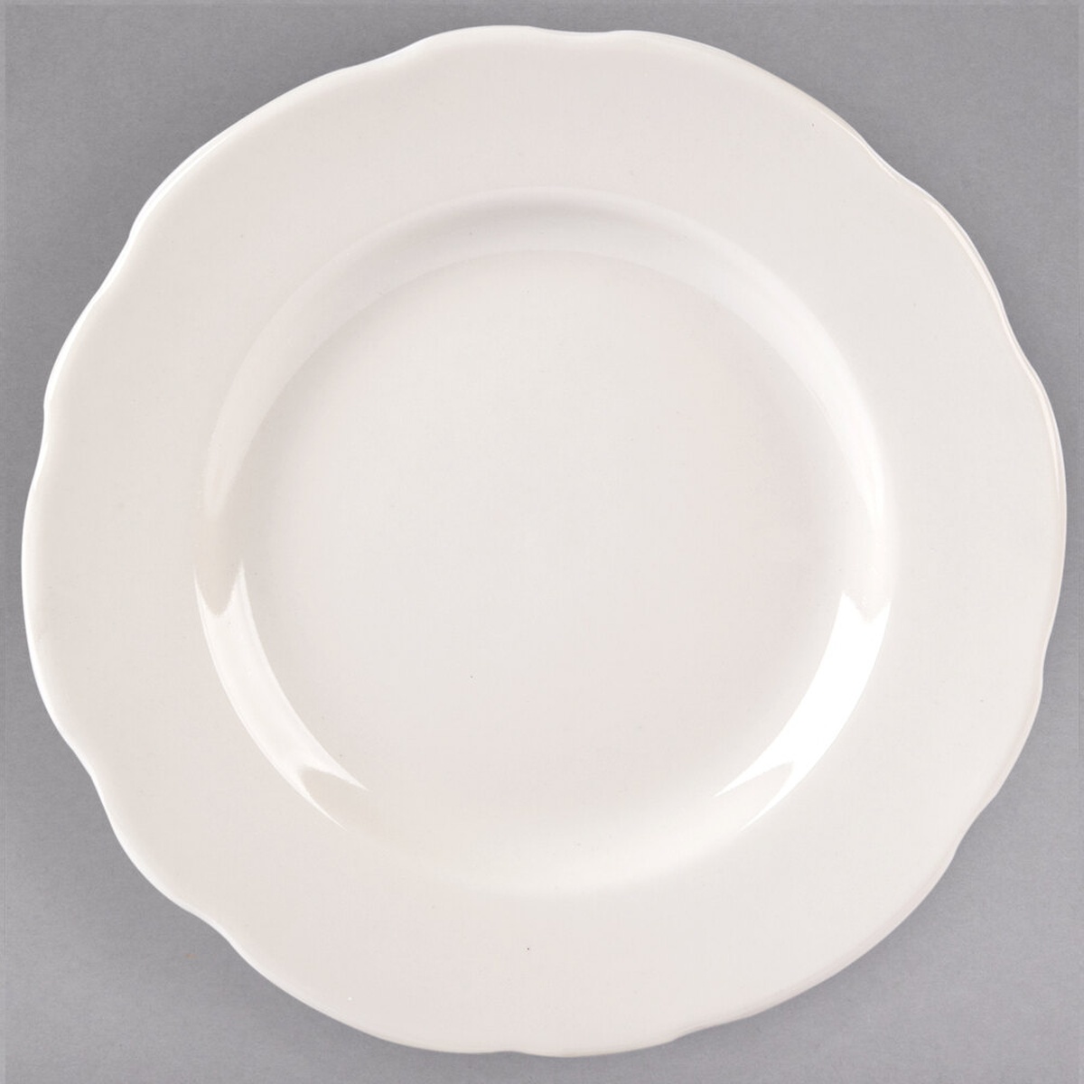Tuxton TSC-006 Shell 6 3/8 inch eggshell scalloped edge china plate, top-down view on gray background
