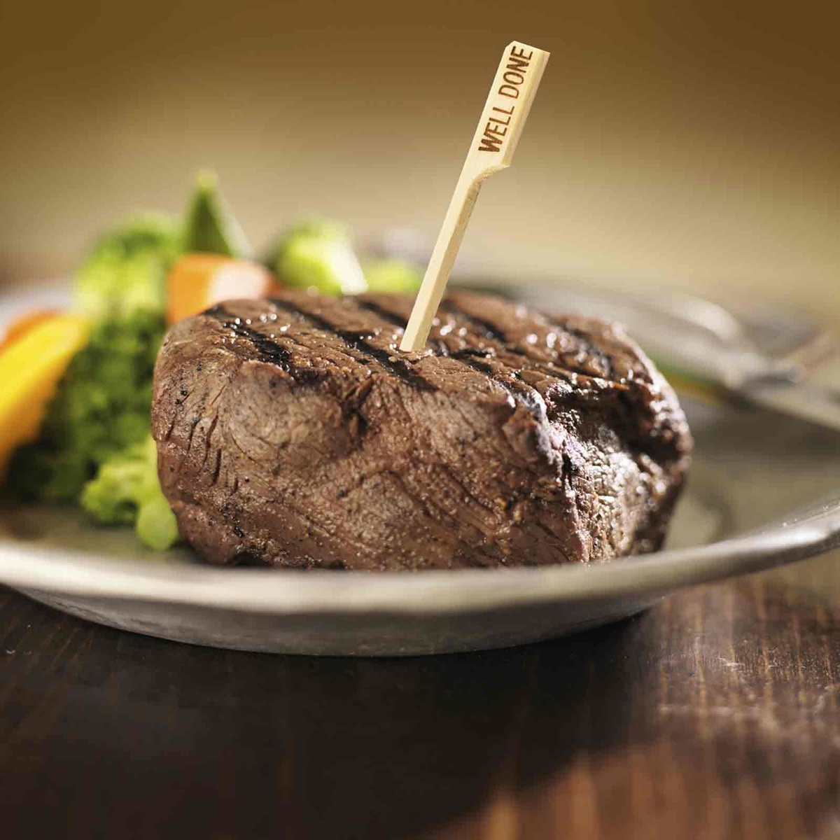 Bamboo steak pick inserted into a grilled steak with vegetables