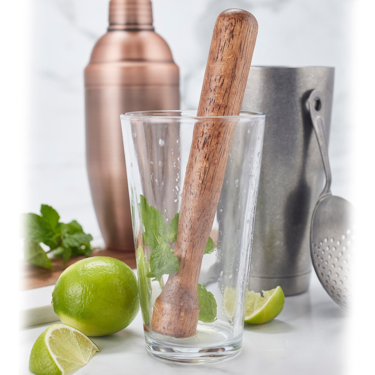 Winco 16 oz mixing glass with muddler and bar tools alongside limes and mint