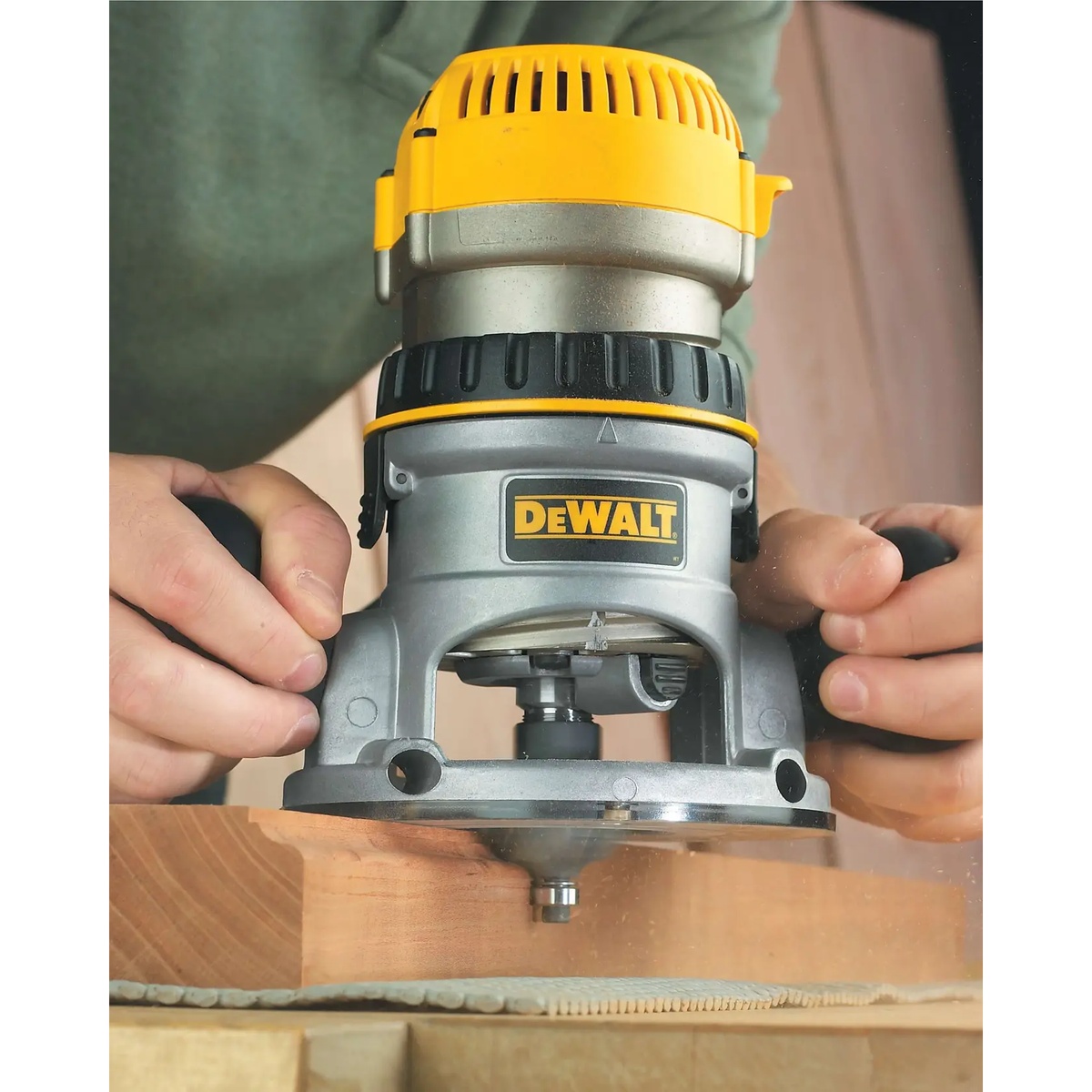 DEWALT DW618 Fixed Base Router trimming the edge of a wood board on a workshop bench during precision woodworking