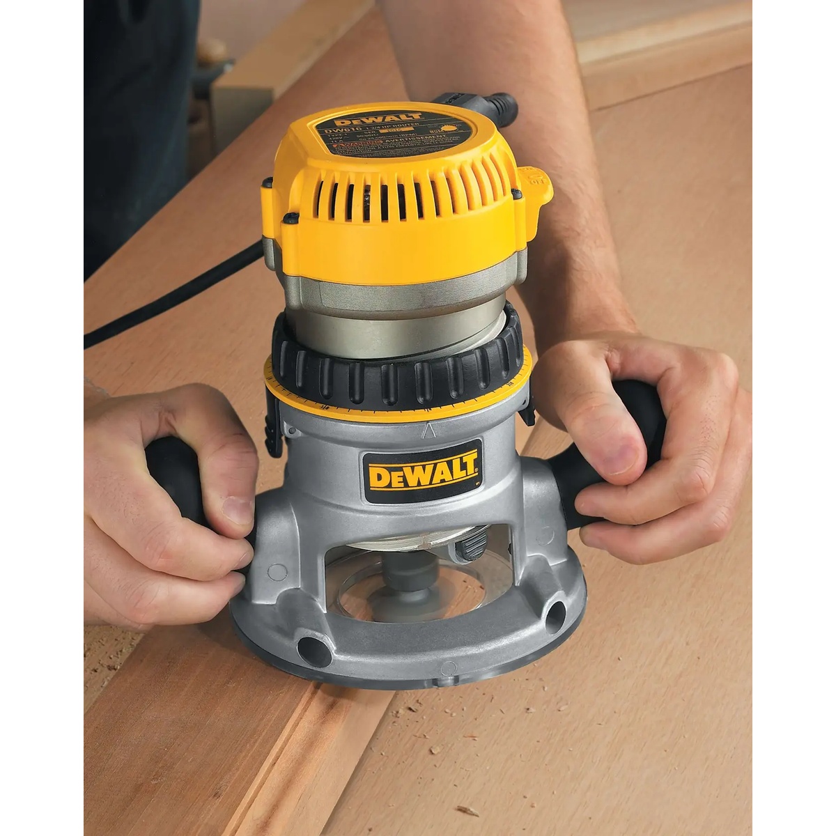 DEWALT DW618 Fixed Base Router making a guided pass across a wood panel for edge shaping in a woodworking shop