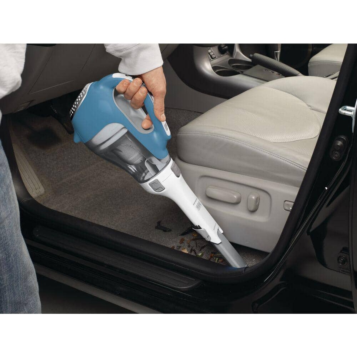 BLACK+DECKER CHV1410L dustbuster handheld vacuum cleaning dry debris from a car floor next to the front seat during interior detailing