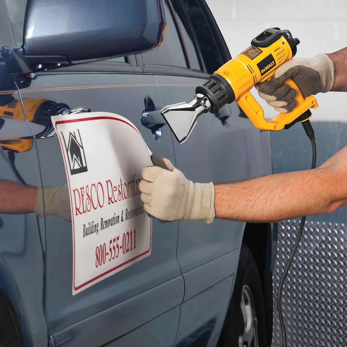 DeWALT D26960K heat gun applying controlled heat to vehicle graphics on a work van door in a shop setting