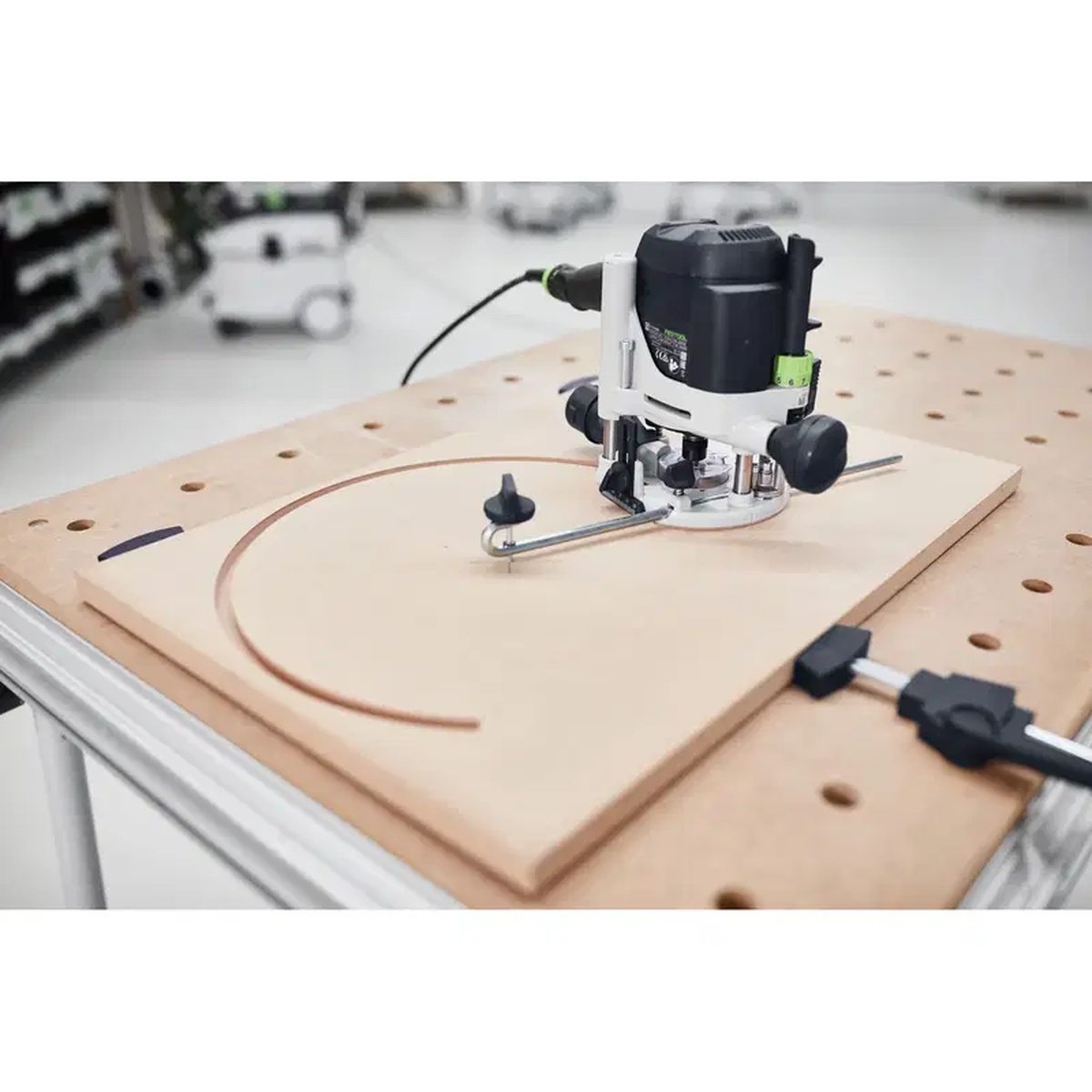 Festool 483922 Trammel Unit OF 1010 attached to a router cutting a wide circular path into a wood panel in a workshop
