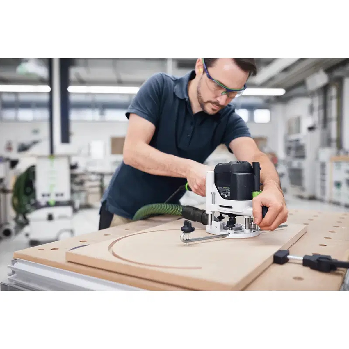 Festool 483922 Trammel Unit OF 1010 guiding a Festool router through a circular cut on a wood panel at a workbench
