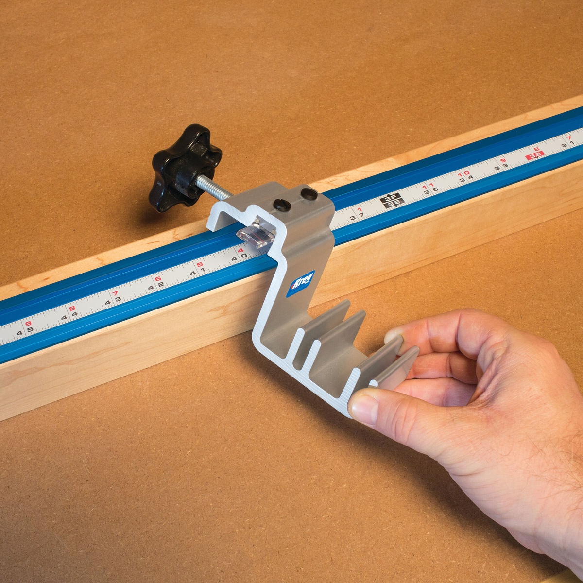 Kreg KMS7800 Production Stop being repositioned by hand in Kreg Top Trak on a workshop fence for quick setup changes